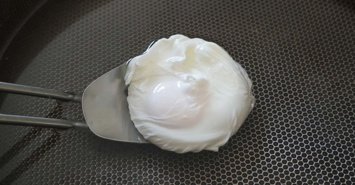 Lifting the poached egg with a slotted spoon